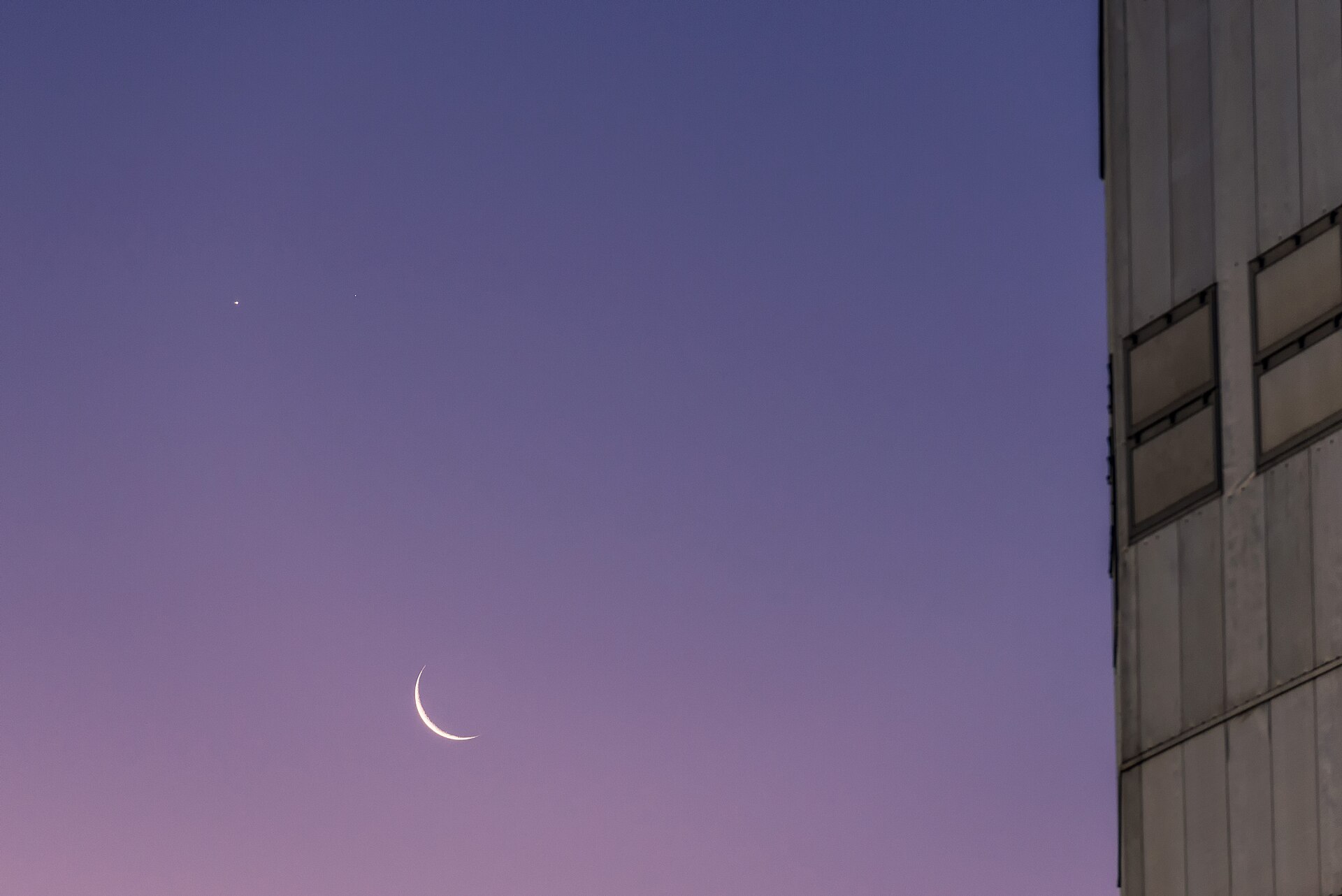 Venus (left) and Mars appear in the sky above the fine arc of a crescent Moon. The figure of one of the VLT's Unit Telescopes fills the right side of the frame.
