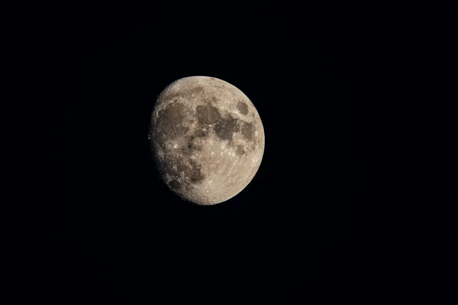 Uma imagem em alta resolução capturando a superfície detalhada da lua contra um céu noturno escuro.