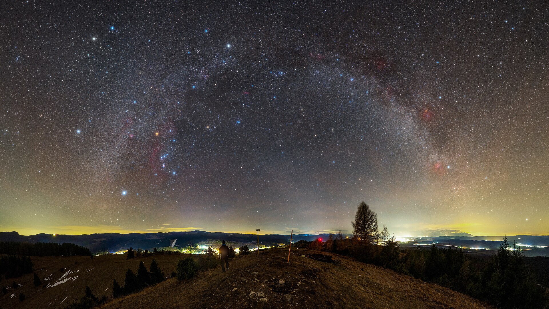 Image title: Warm Winter Night Over Spiš RegionAuthor: Robert BarsaCountry: SlovakiaThis image, taken in Slovakia in January 2022, shows regions of the Milky Way and a rich variety of constellations. The summer constellations of the northern hemisphere are very low in the sky towards the bottom-right. The bright stars of Cygnus and Lyra shine through the artificial lights at the horizon. The huge array of northern winter and autumn constellations with many bright stars are associated with divers