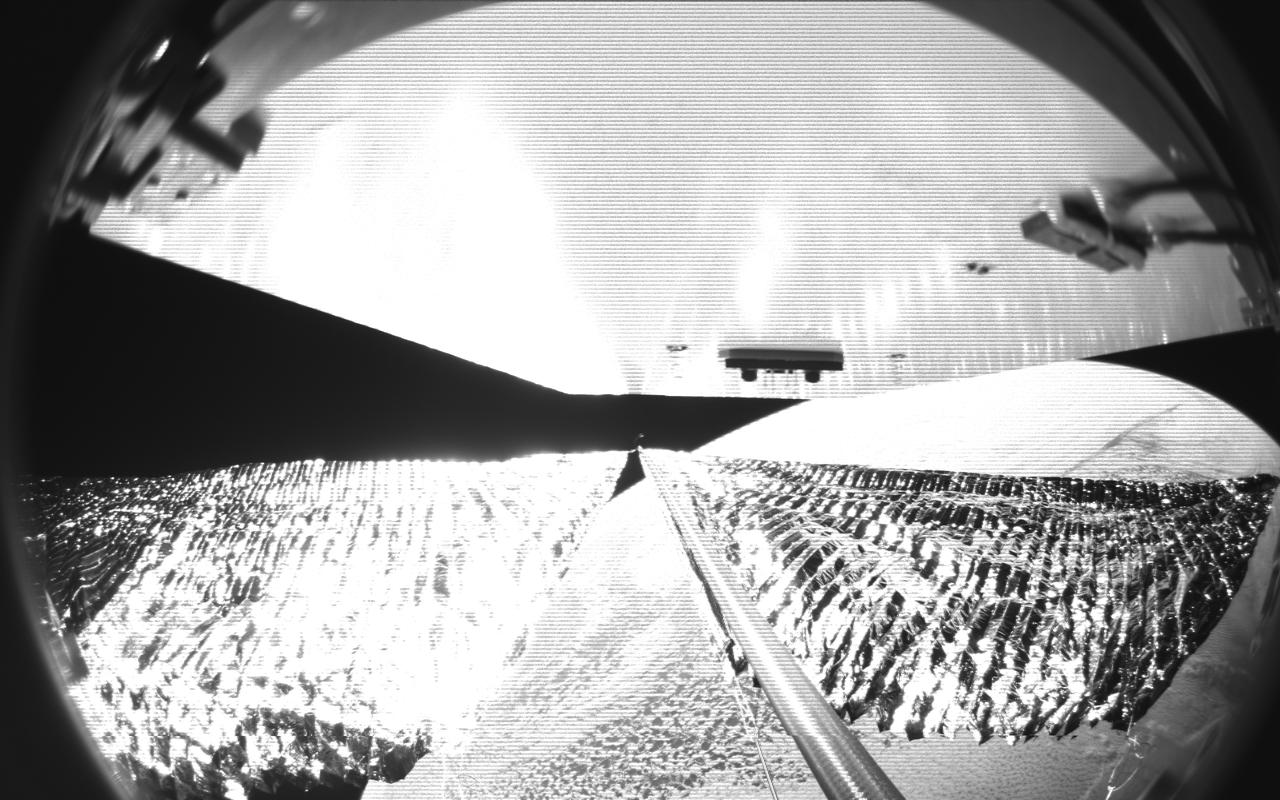Four cameras aboard the Advanced Composite Solar Sail System spacecraft show the four reflective sail quadrants supported by composite booms. The booms are mounted at right angles and the spacecraft’s solar panel is rectangular, but lines appear distorted because of the wide-angle camera field of view. View from a black-and-white wide-angle camera aboard the Advanced Composite Solar Sail System taken during sail unfurling in low Earth orbit. The spacecraft has four such cameras, centrally locate