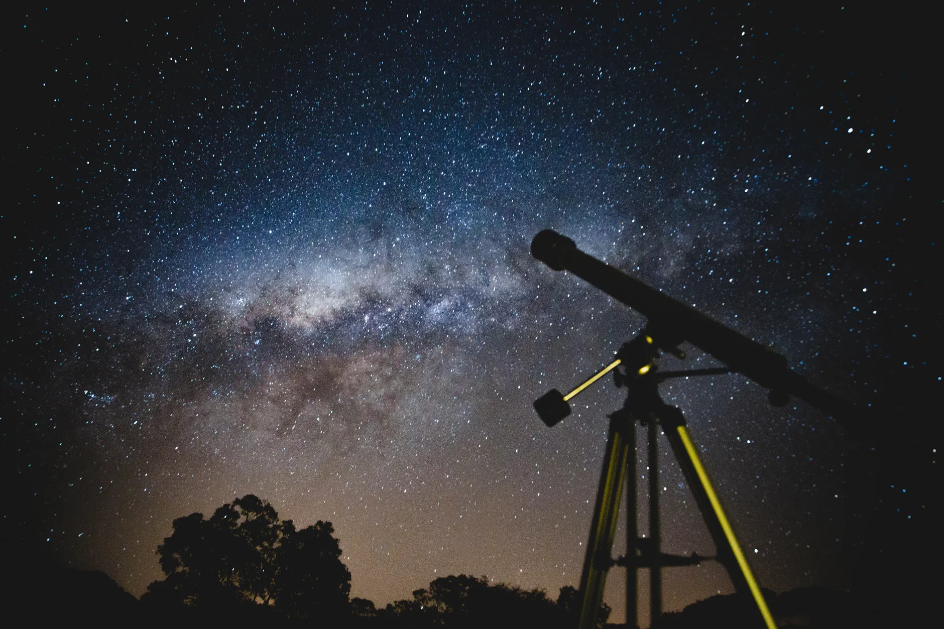 Deslumbrante céu estrelado com silhueta de telescópio capturando a Via Láctea no Brasil.